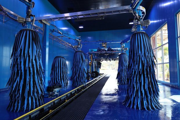 Ottos car wash floridaBlue car wash tunnel with hanging rotating brush rollers and bright light at the exit