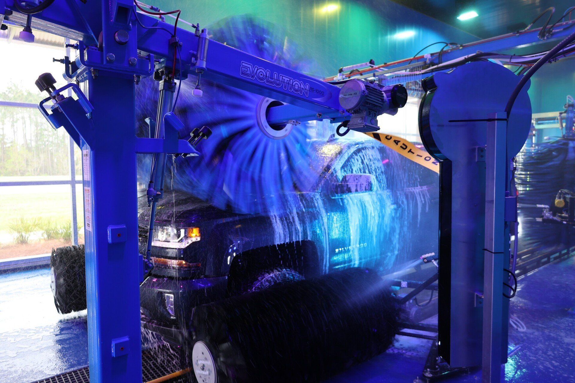 Ottos car wash floridaBlue car wash tunnel spraying water and soap over a vehicle under bright neon lights