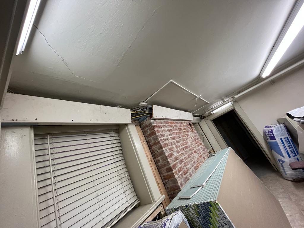Interior view with brick wall, blinds, and white ceiling with fluorescent lights.