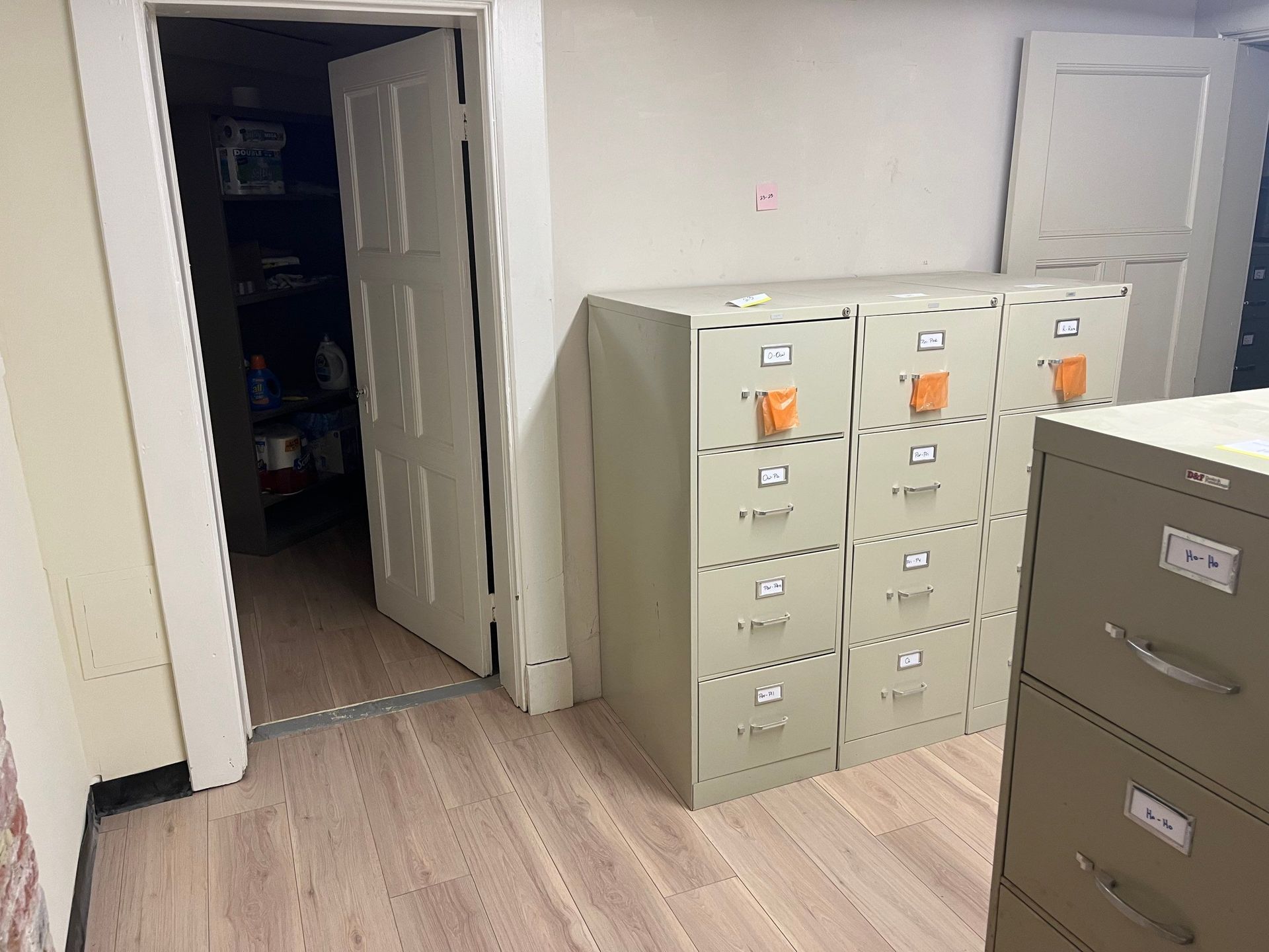 A room with filing cabinets and an open door to a storage area.