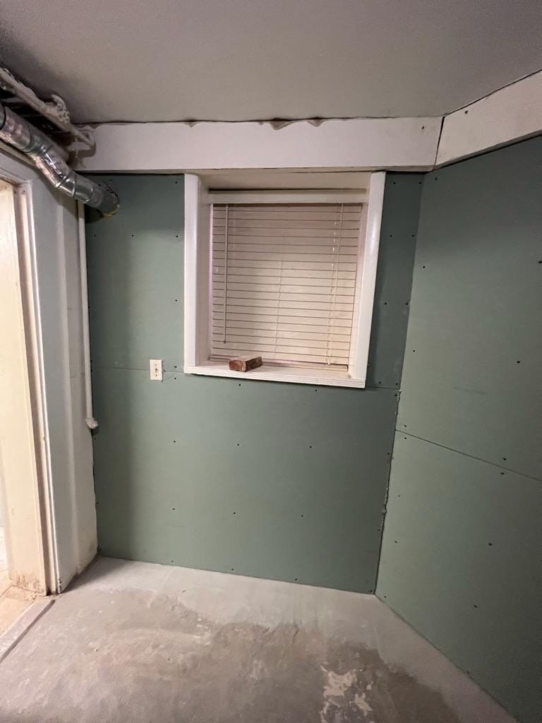 Green drywall room with a window, white trim, and concrete floor.