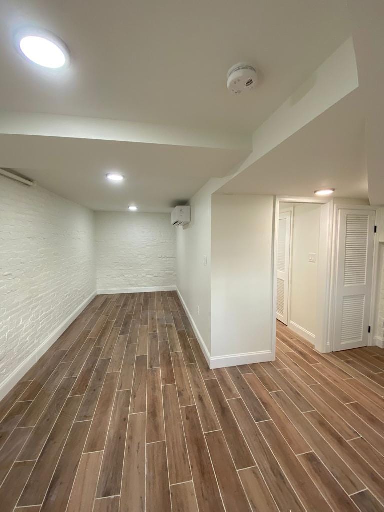 Empty room with wood-look flooring and white walls. Includes doors and recessed lighting.
