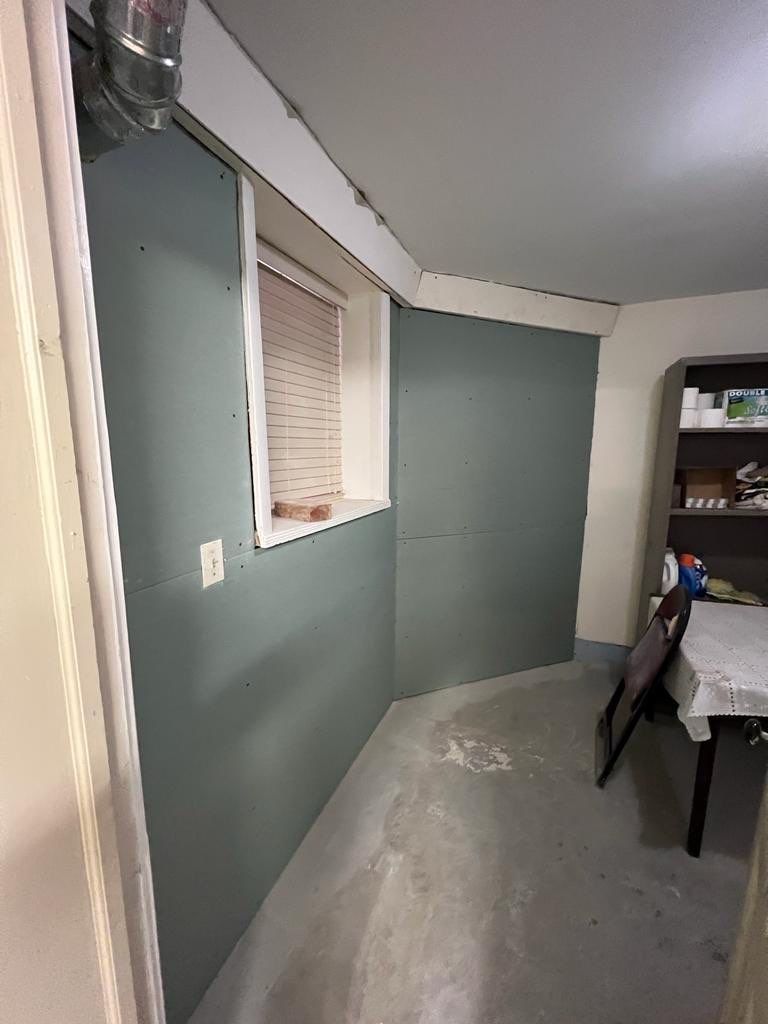 Interior view: drywall walls, window, electrical outlet, and a gray concrete floor in a room.