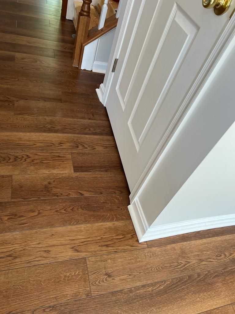 Wooden floor with a white door and staircase.