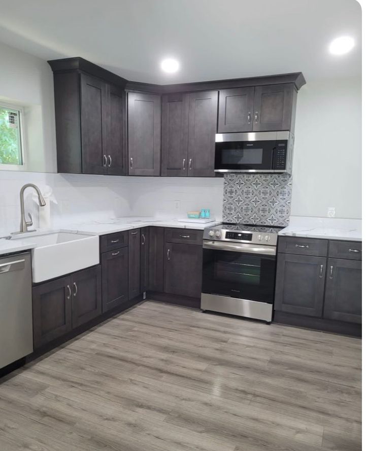 Dark gray kitchen cabinets with stainless steel appliances and white countertops.