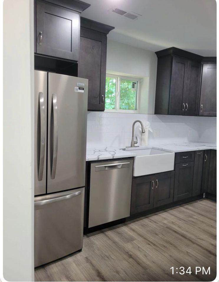 Stainless steel kitchen with dark gray cabinets, white countertop, and stainless steel appliances.