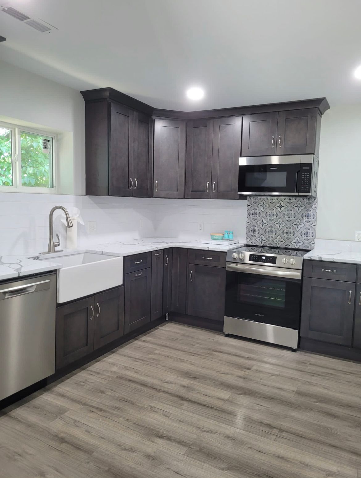 Dark gray kitchen cabinets with stainless steel appliances and white countertops.