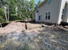 Construction site beside a house with a trench dug in the dirt.
