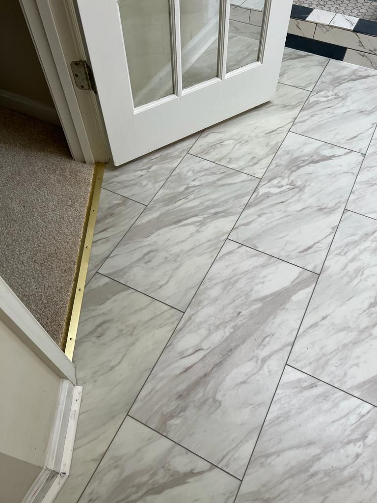 White and gray marbled tile flooring with a doorway and carpeted entry.