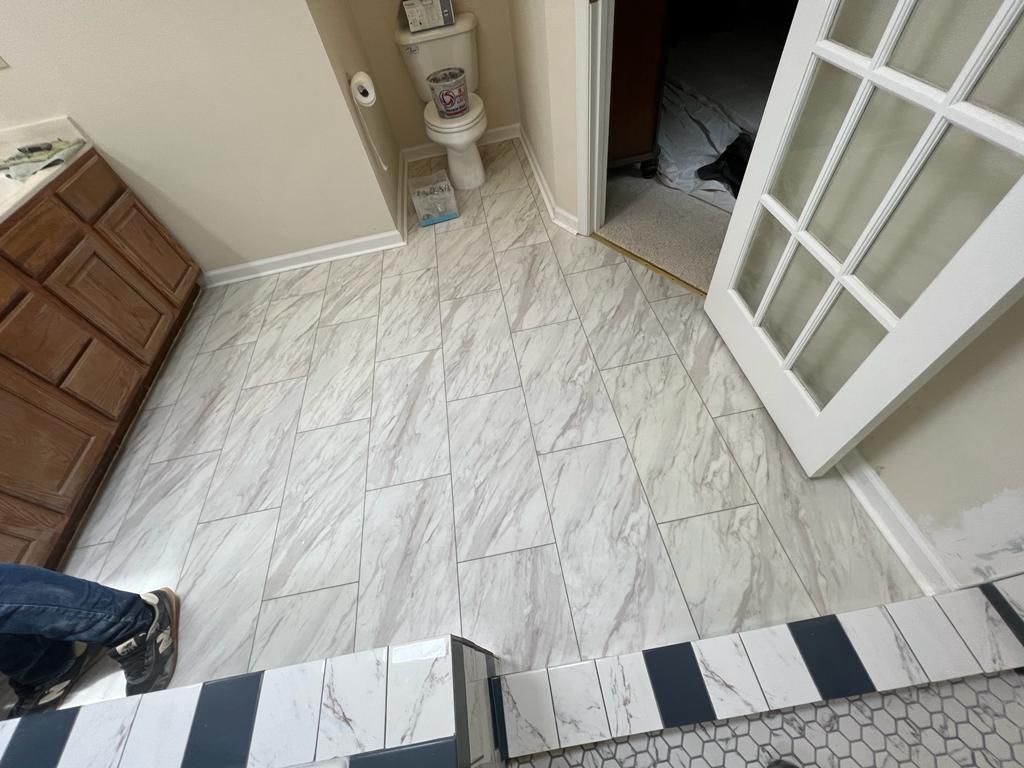 Bathroom with new marble-look tile flooring.  Doorway, vanity, and toilet visible.