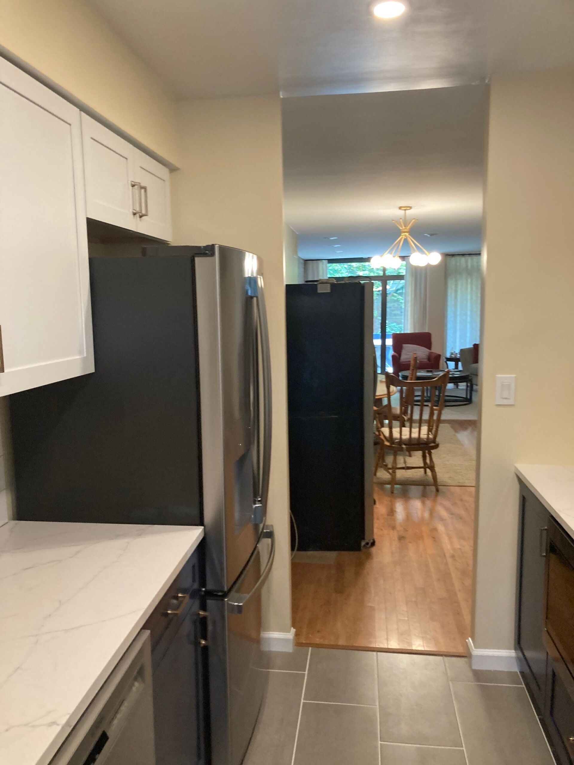 Kitchen with white cabinets, stainless steel refrigerator, and opening to dining area.