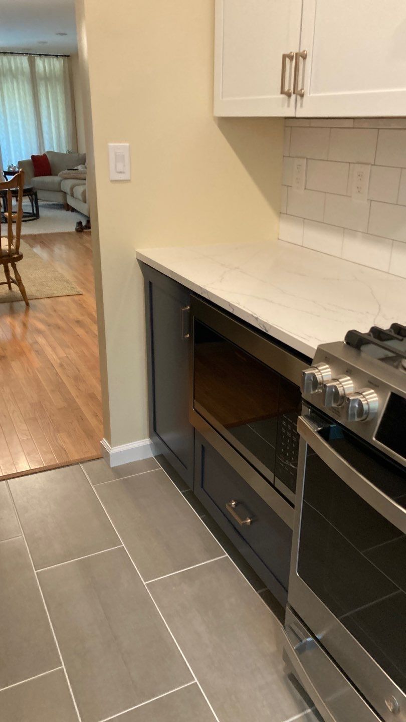Kitchen with gray cabinets, a built-in microwave, white countertop, and stainless steel range.