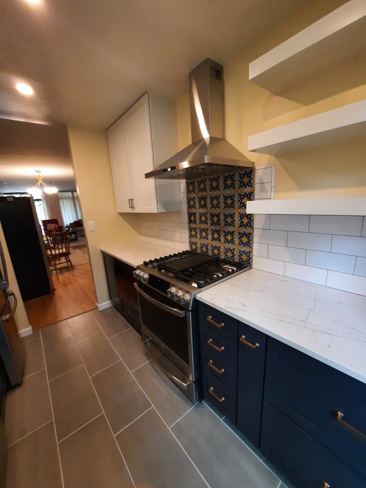 Modern kitchen with navy cabinets, stainless steel appliances, and tile backsplash.