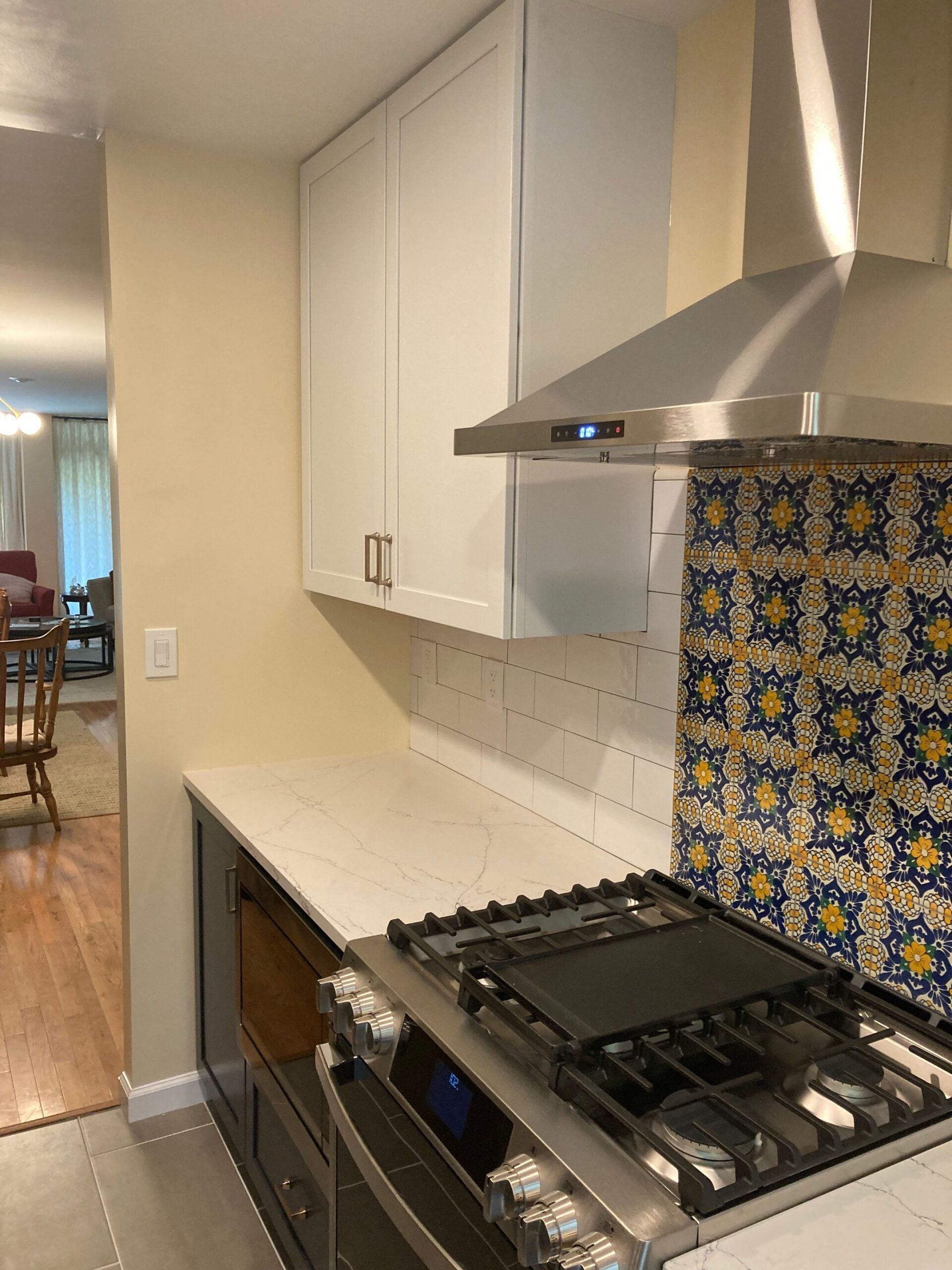Kitchen with white cabinets, stovetop, and patterned backsplash.