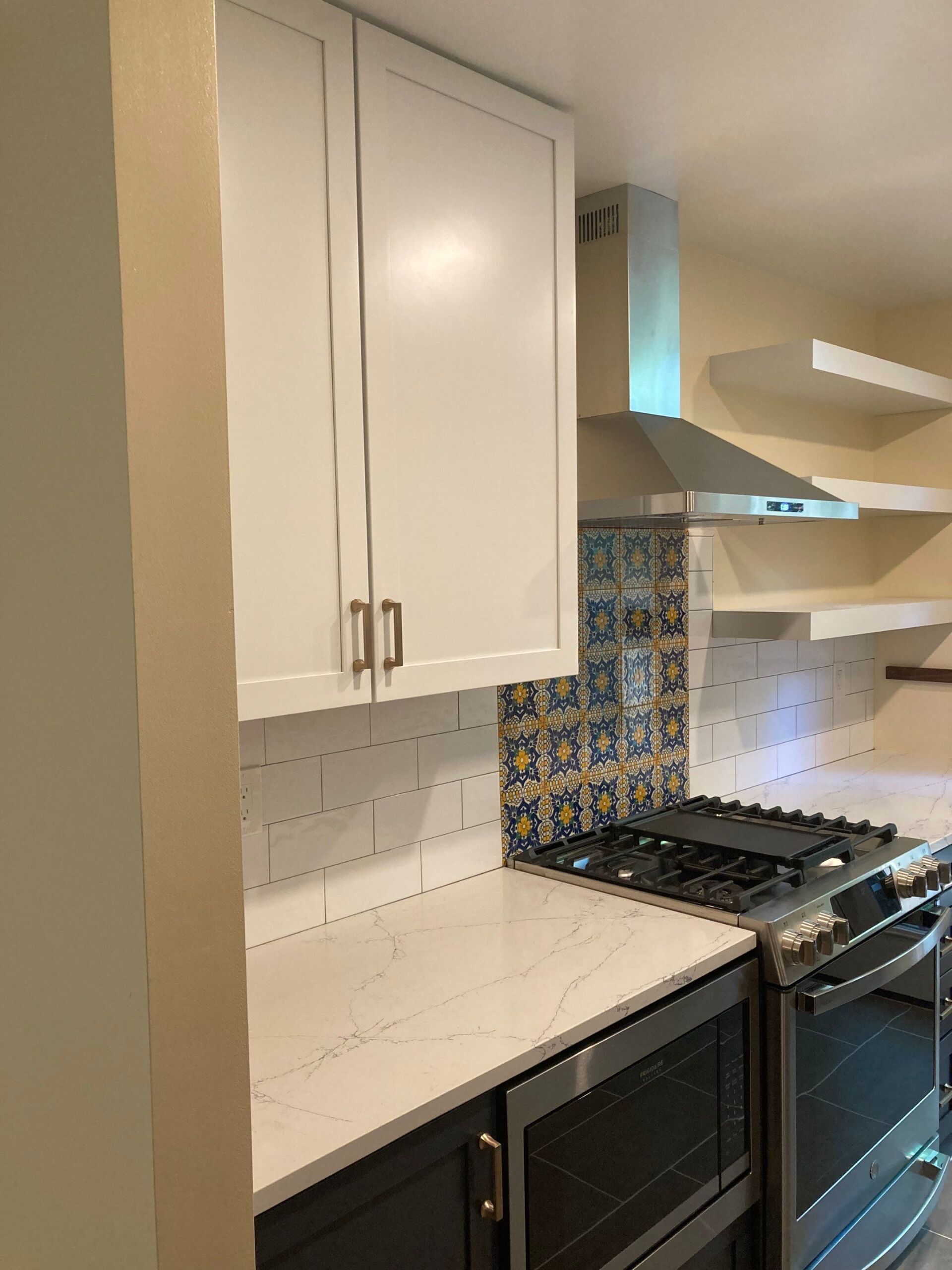 Modern kitchen with white cabinets, stainless steel appliances, and patterned backsplash.