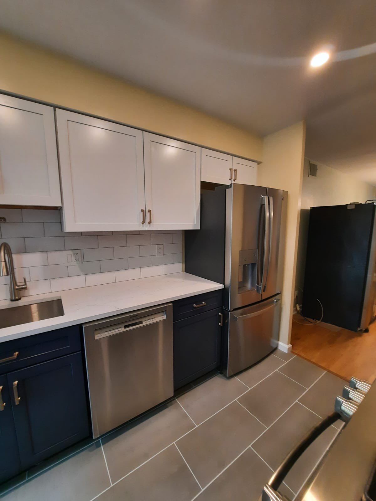 Kitchen with blue and white cabinets, stainless steel appliances, and gray tile floor.
