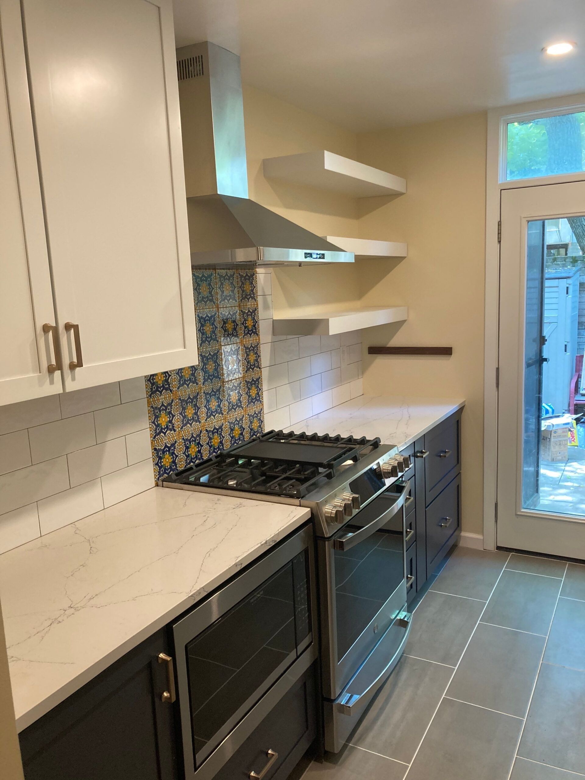 Kitchen with white and gray cabinets, stainless steel appliances, and open shelving.