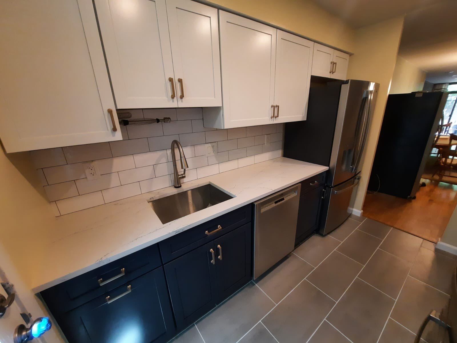 Kitchen with white and blue cabinets, stainless steel appliances, and gray tile floor.