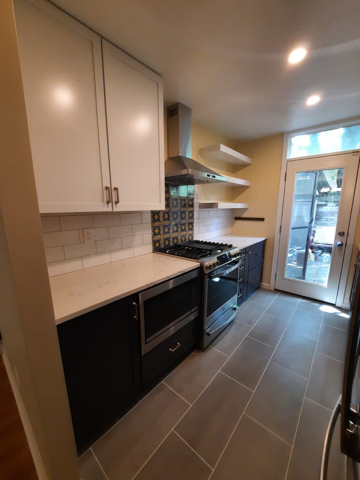 Modern kitchen with white and black cabinets, stainless steel appliances, and gray tile flooring.