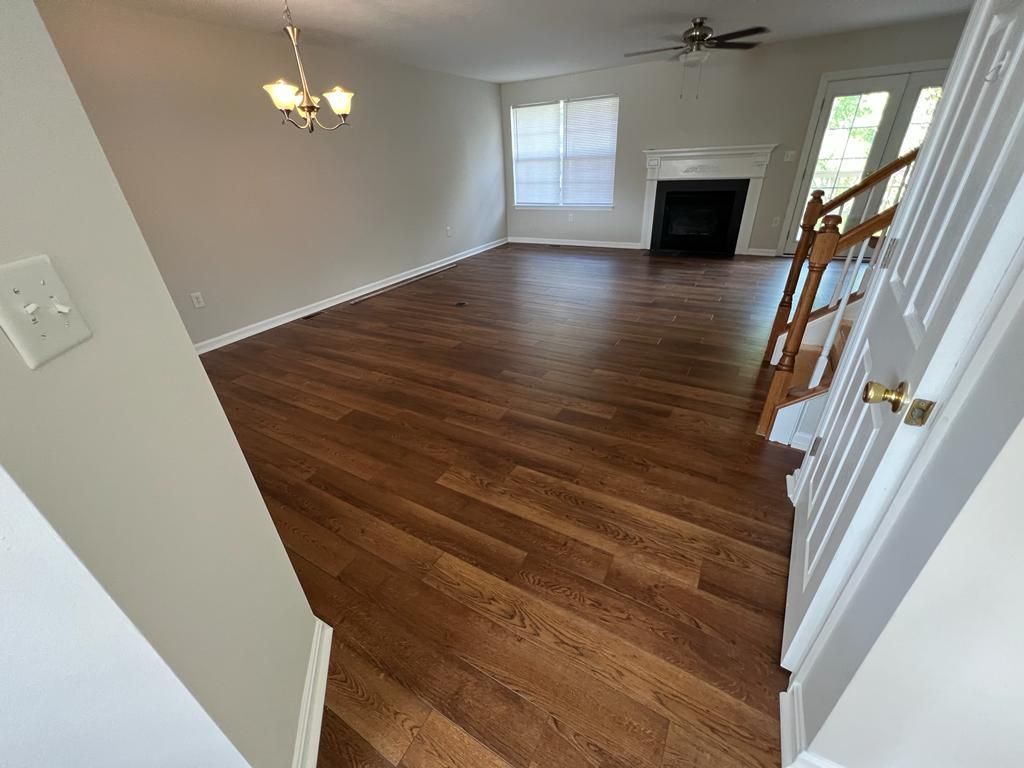 Living room with hardwood floors, fireplace, and stairs leading up.