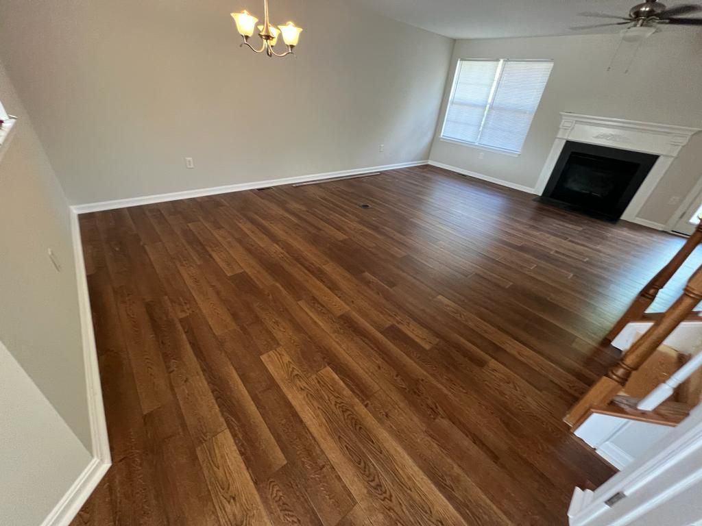 Living room with dark wood flooring, fireplace, and chandelier.