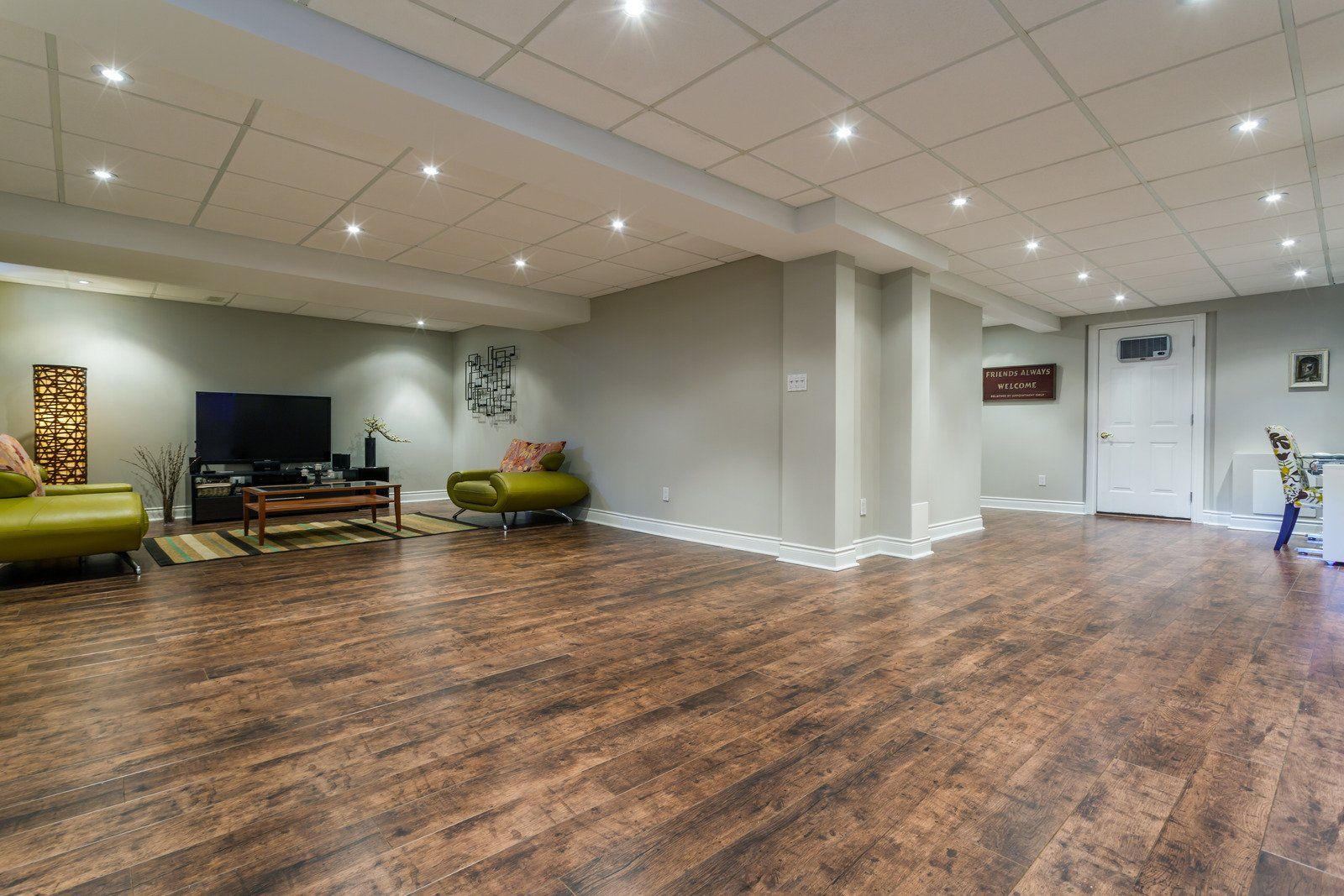 Spacious basement with wood-look flooring, light green walls, and recessed lighting.