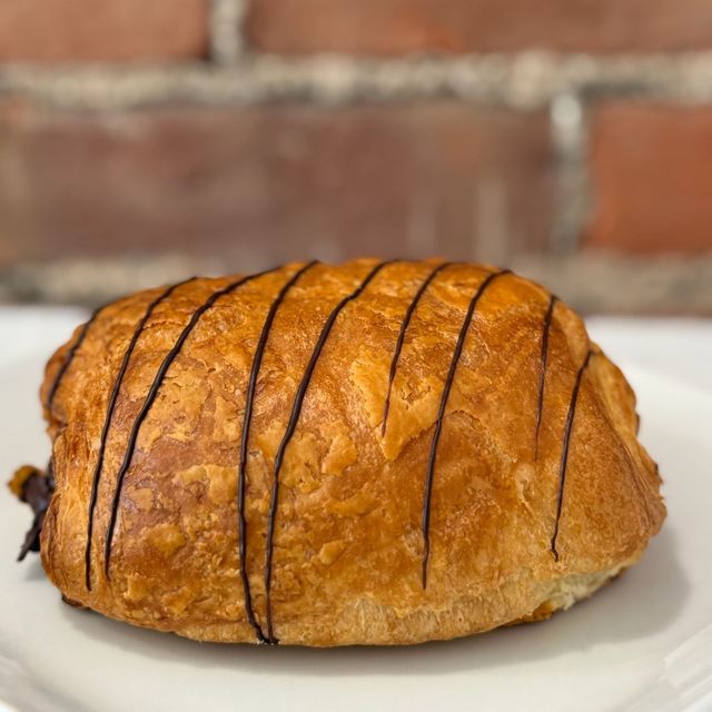 A pastry with chocolate stripes on it is on a white plate.
