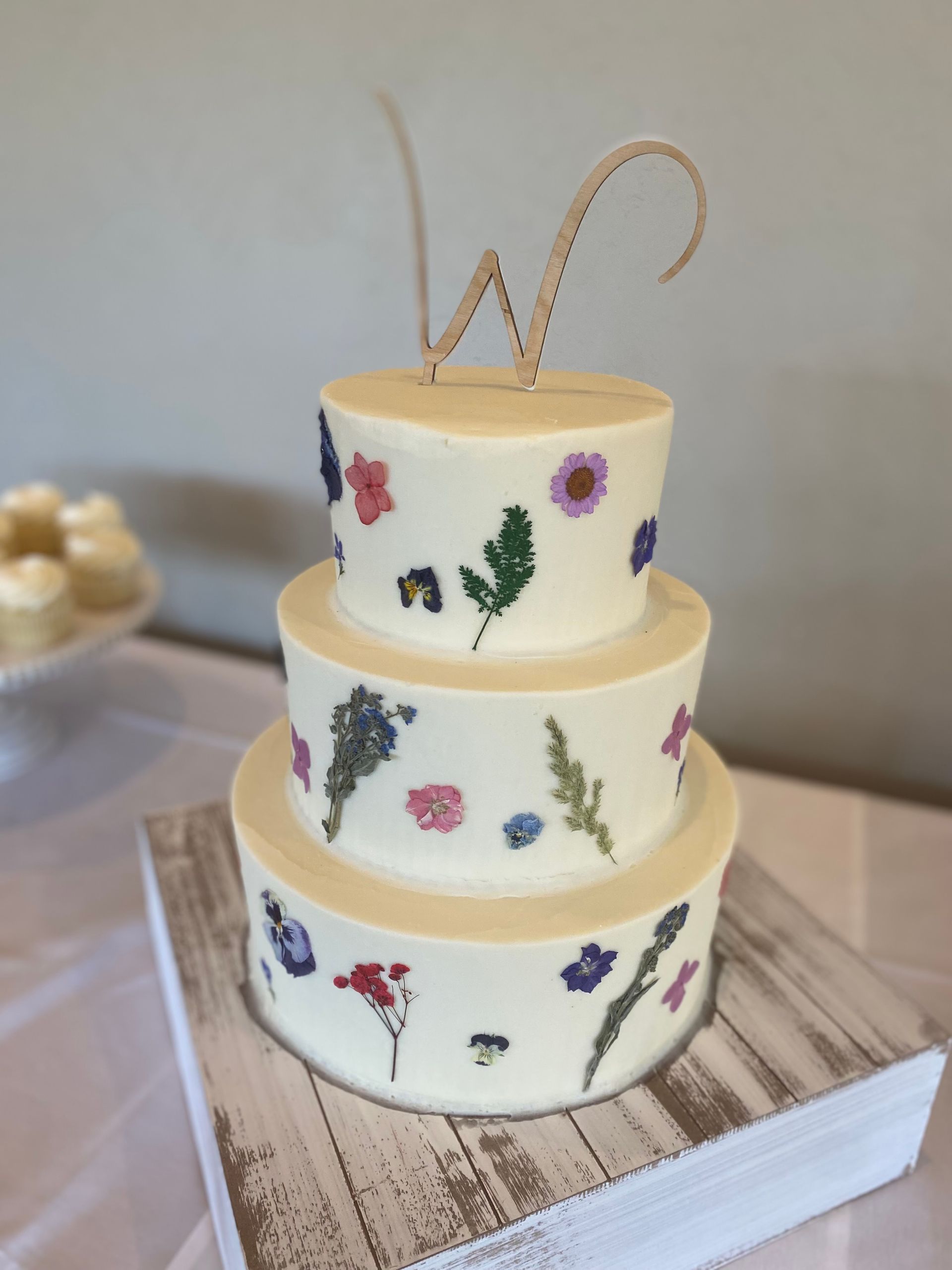 A white cake with flowers on it and the letter w on top