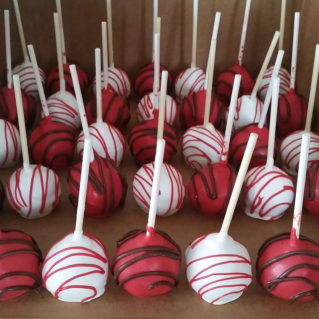 A box of red and white cake pops on sticks
