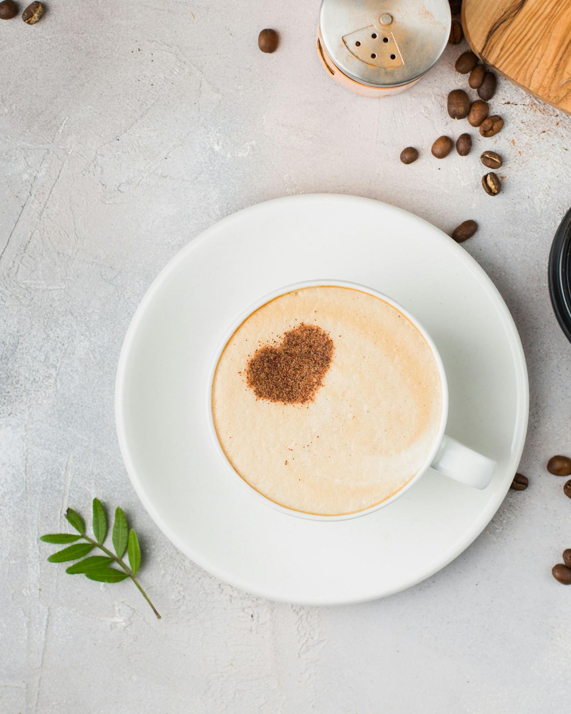 A cup of coffee with a heart in the foam on a saucer.