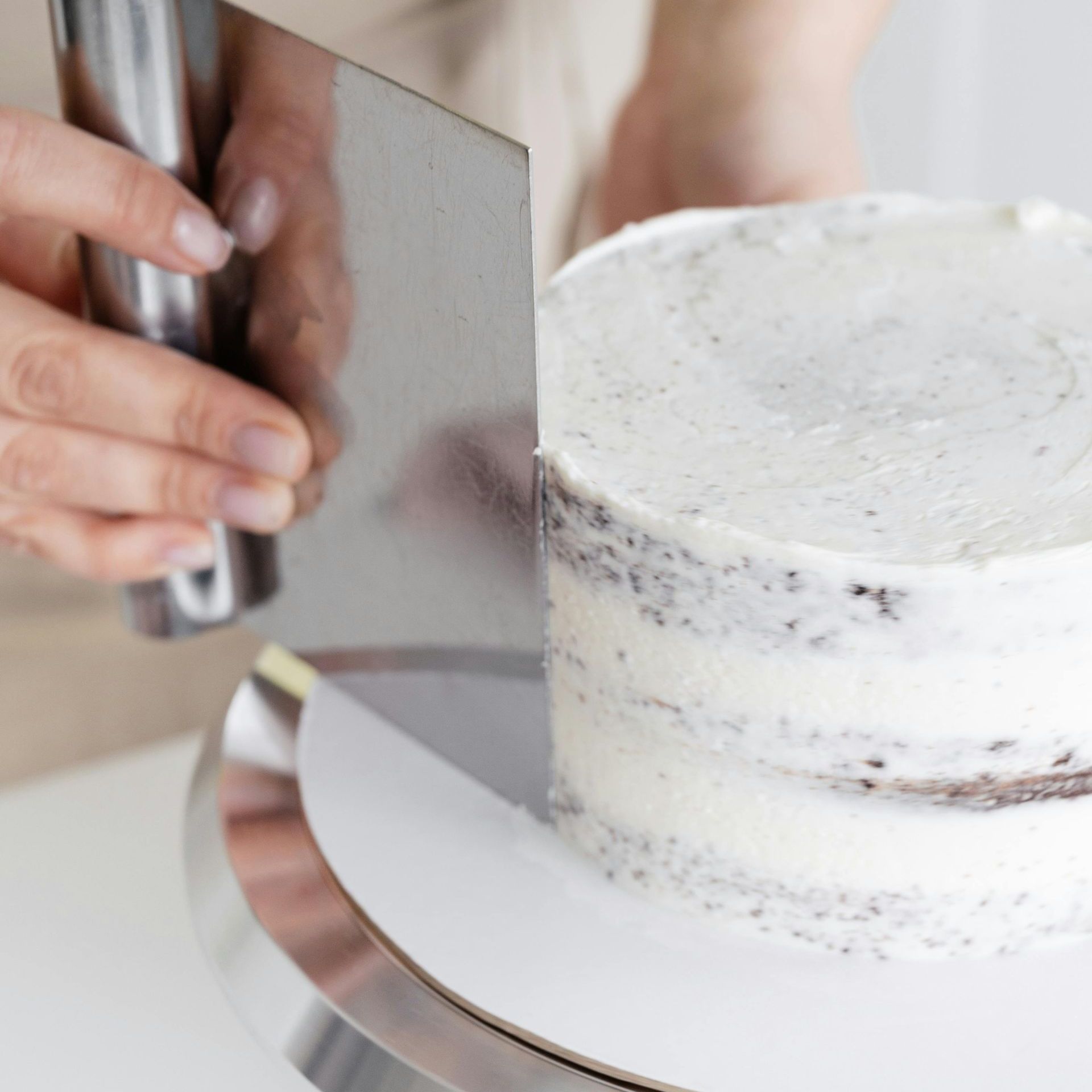A person is frosting a cake with a spatula