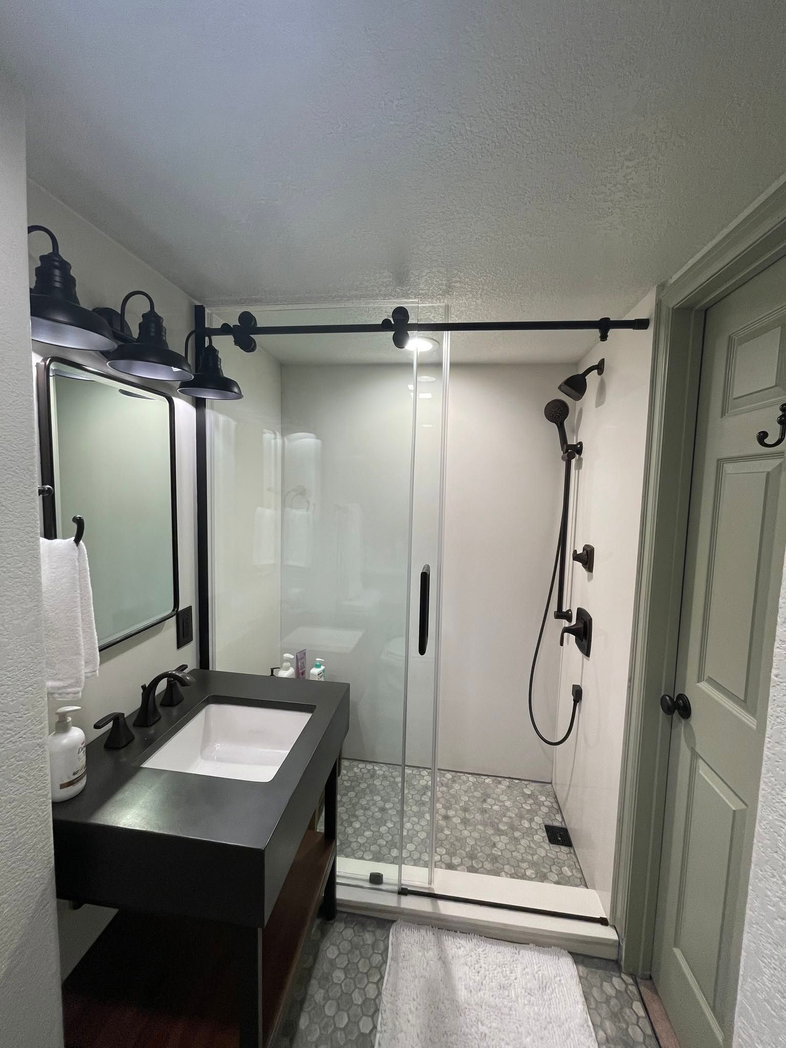 Modern bathroom with glass shower, vanity sink, mirror, and patterned tile floor
