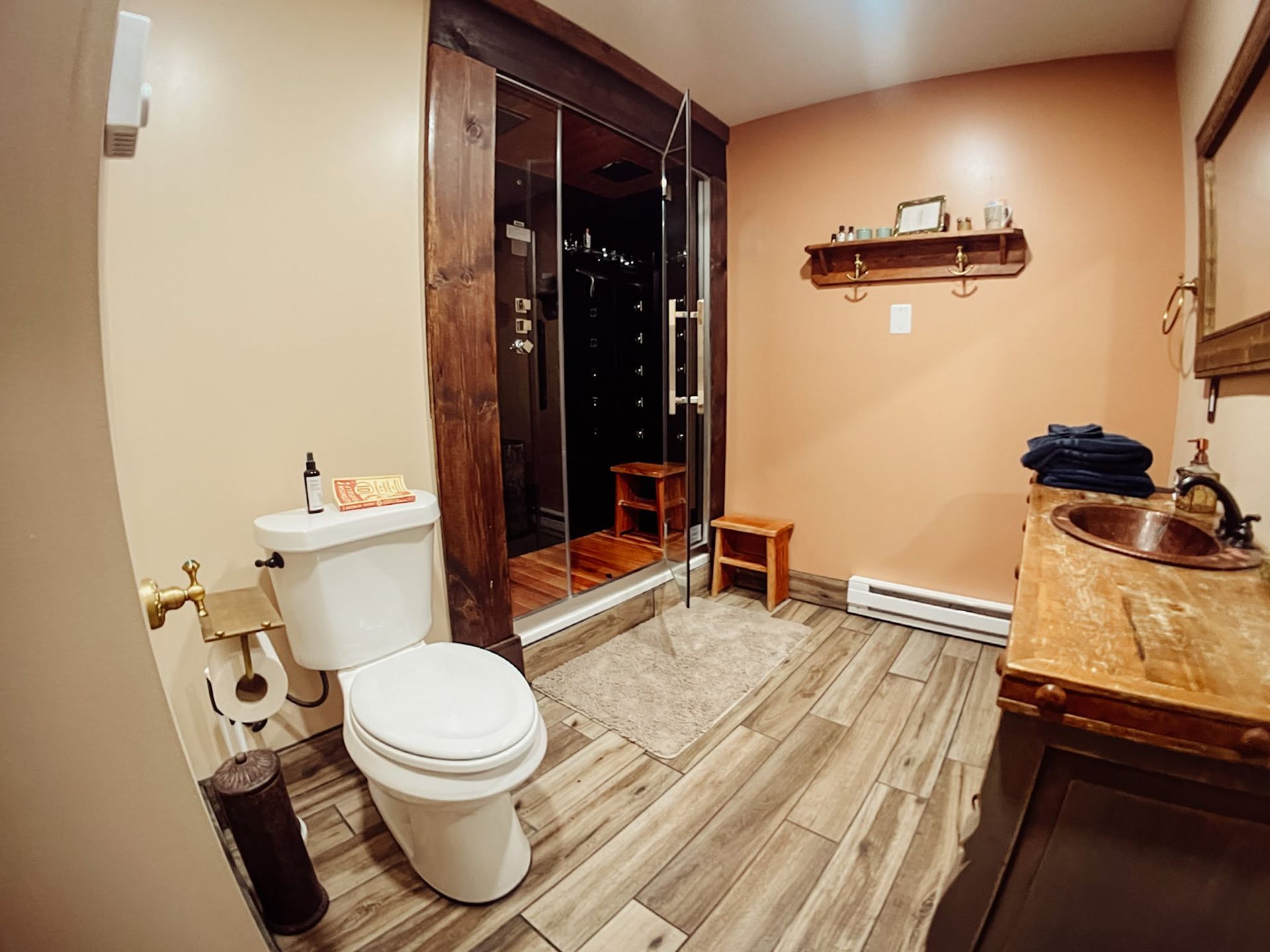 Rustic bathroom with toilet, glass shower, wood vanity, and beige walls