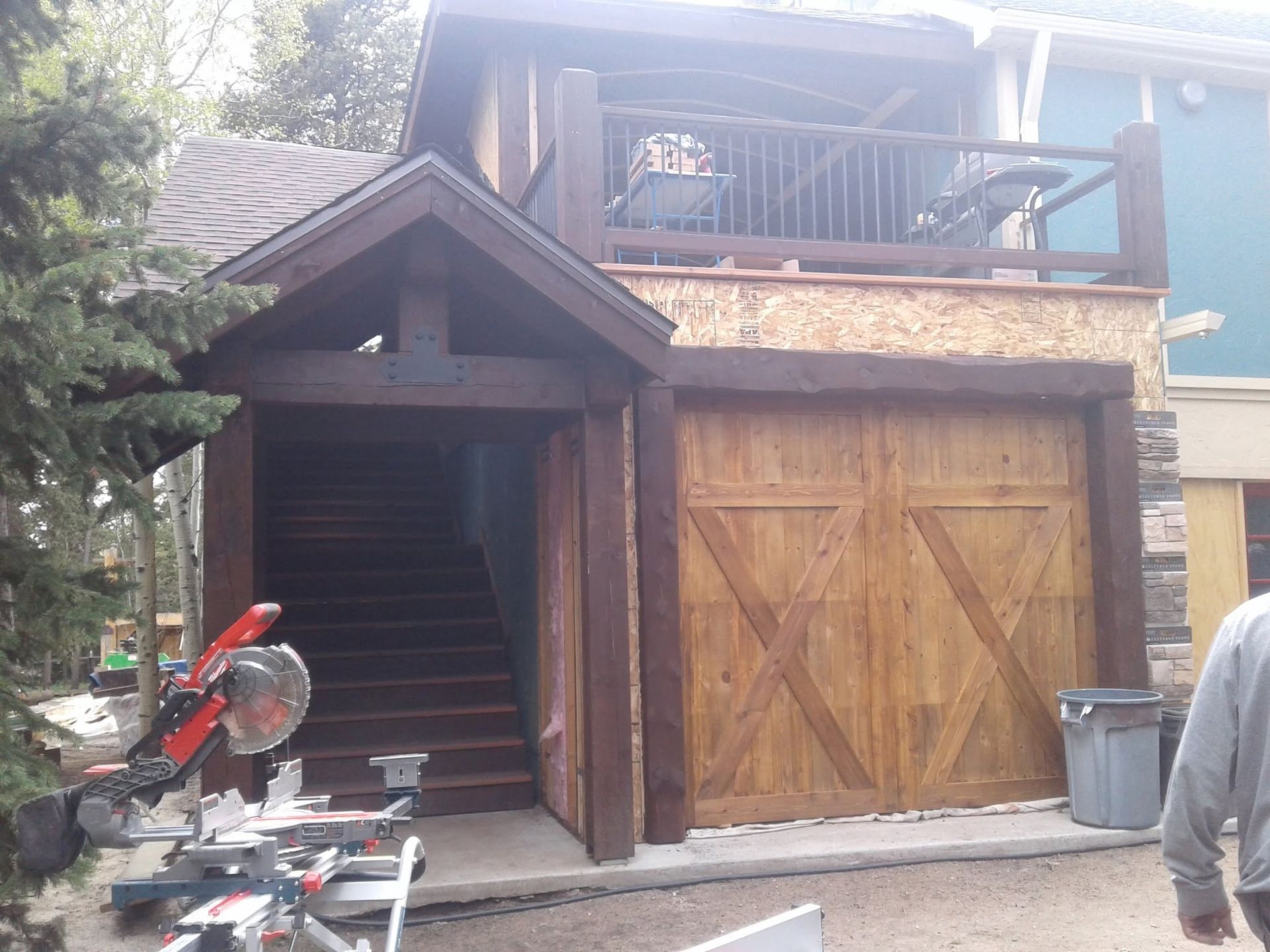Wooden garage with large double door and scooter parked outside under a covered entry