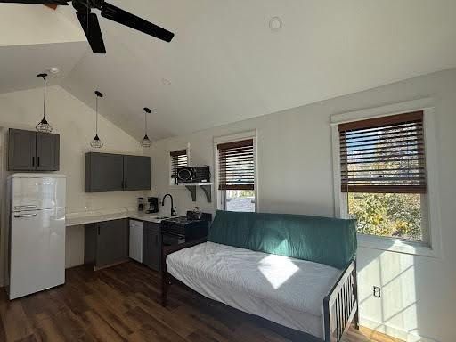 Compact studio apartment with kitchenette, futon, wood floors, ceiling fan, and two windows with blinds