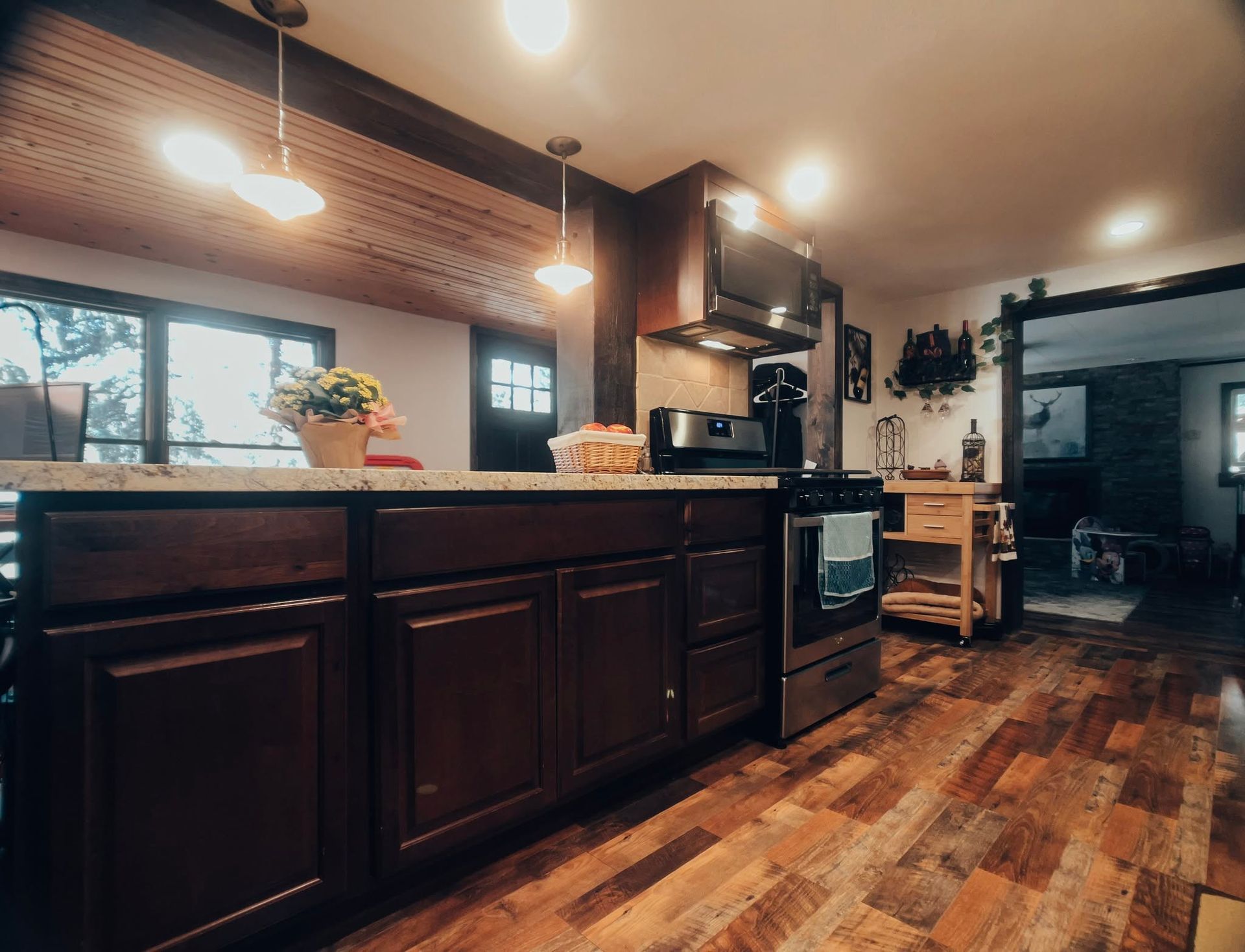 Warm kitchen with dark wood cabinets, hardwood floors, island, and pendant lights in a rustic home interior.
