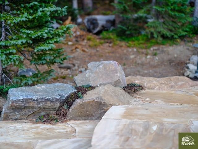 Boulders and a small stream in a rocky garden surrounded by green foliage