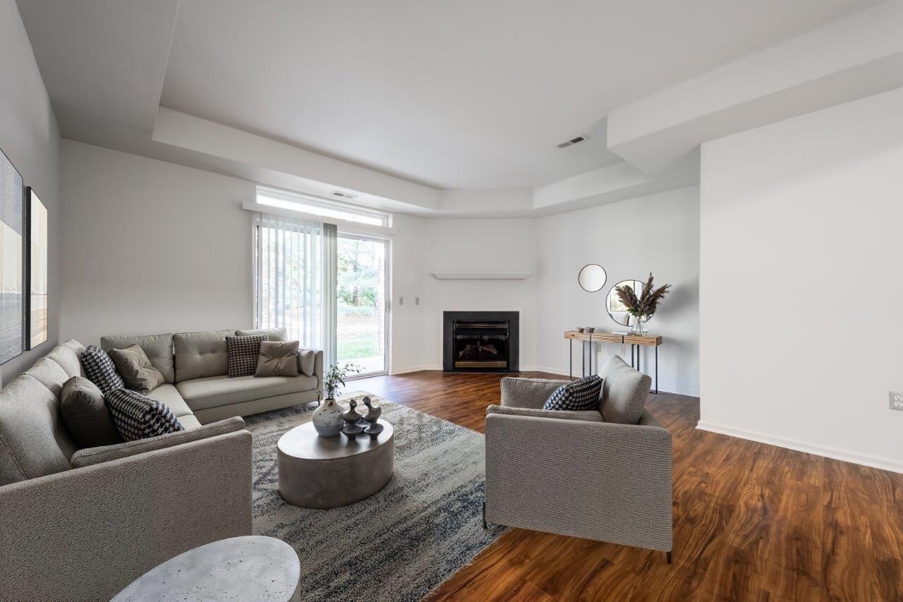 Spacious modern apartment living room with gray sectional, two chairs, fireplace, and sliding glass door. Visit us at Fox Ridge & Lakeview Park Apartments and view our apartments for rent in Limerick, PA.