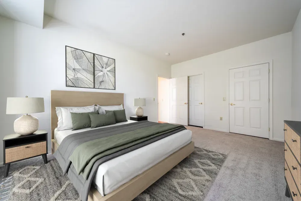Modern bedroom in an apartment with a large bed, two nightstands, and neutral decor. Visit us at Fox Ridge & Lakeview Park Apartments and view our modern, garden-style 1 and 2 bedroom apartments in Limerick, PA.