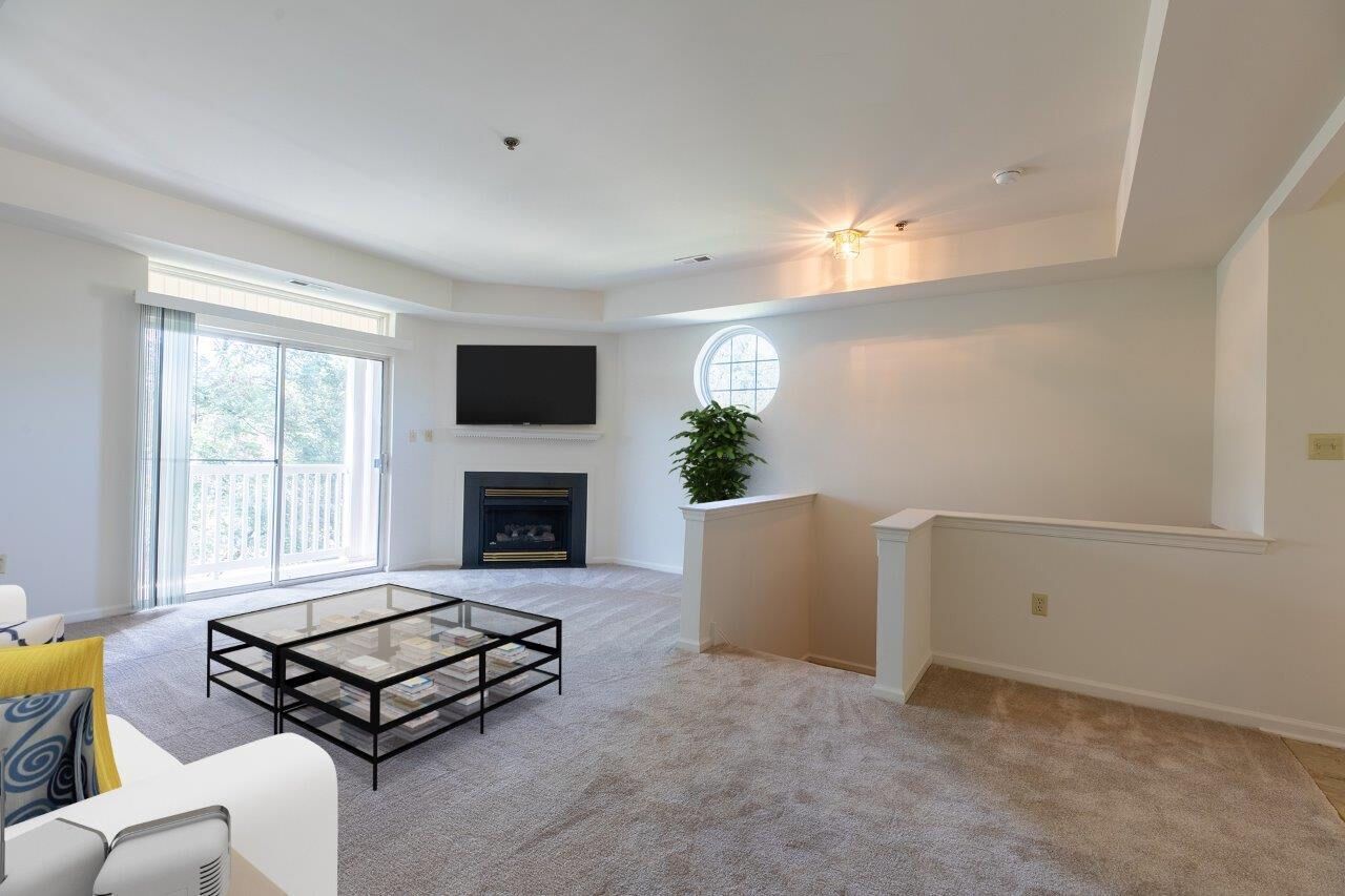 Bright living room with a fireplace, wall-mounted TV, and balcony door. Visit us at Fox Ridge & Lakeview Park Apartments and view our pet-friendly apartments for rent in Limerick, PA.