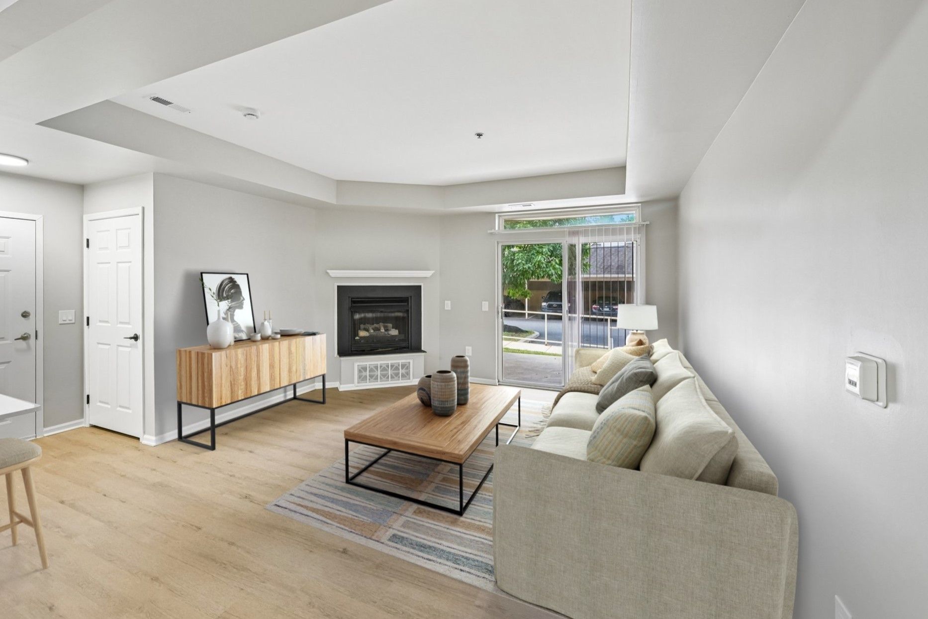 Bright living room with gray sofa, coffee table, fireplace, and sliding doors to a patio