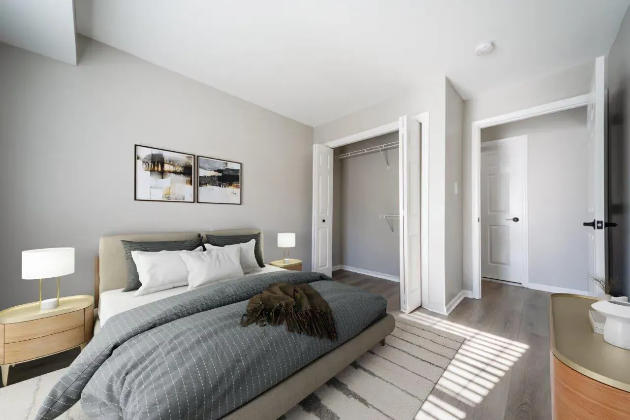 Modern apartment bedroom with a large bed, two nightstands, and an open closet. Visit us at Fox Ridge & Lakeview Park Apartments and view our modern, garden-style 1 and 2 bedroom apartments in Limerick, PA.