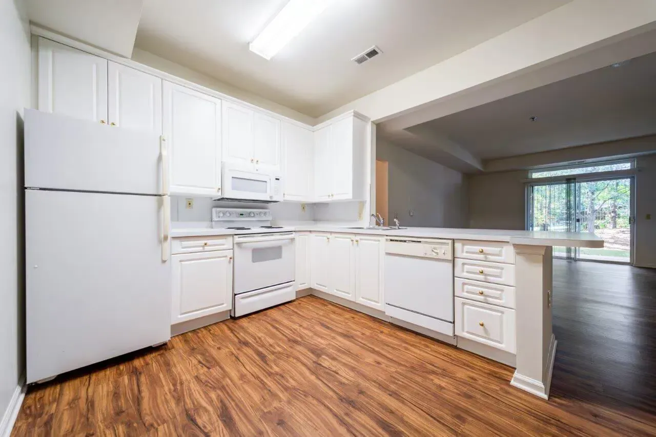White kitchen with refrigerator, stove, microwave, dishwasher, and wood-look flooring. Visit us at Fox Ridge & Lakeview Park Apartments and view our apartments for rent in Limerick, PA.