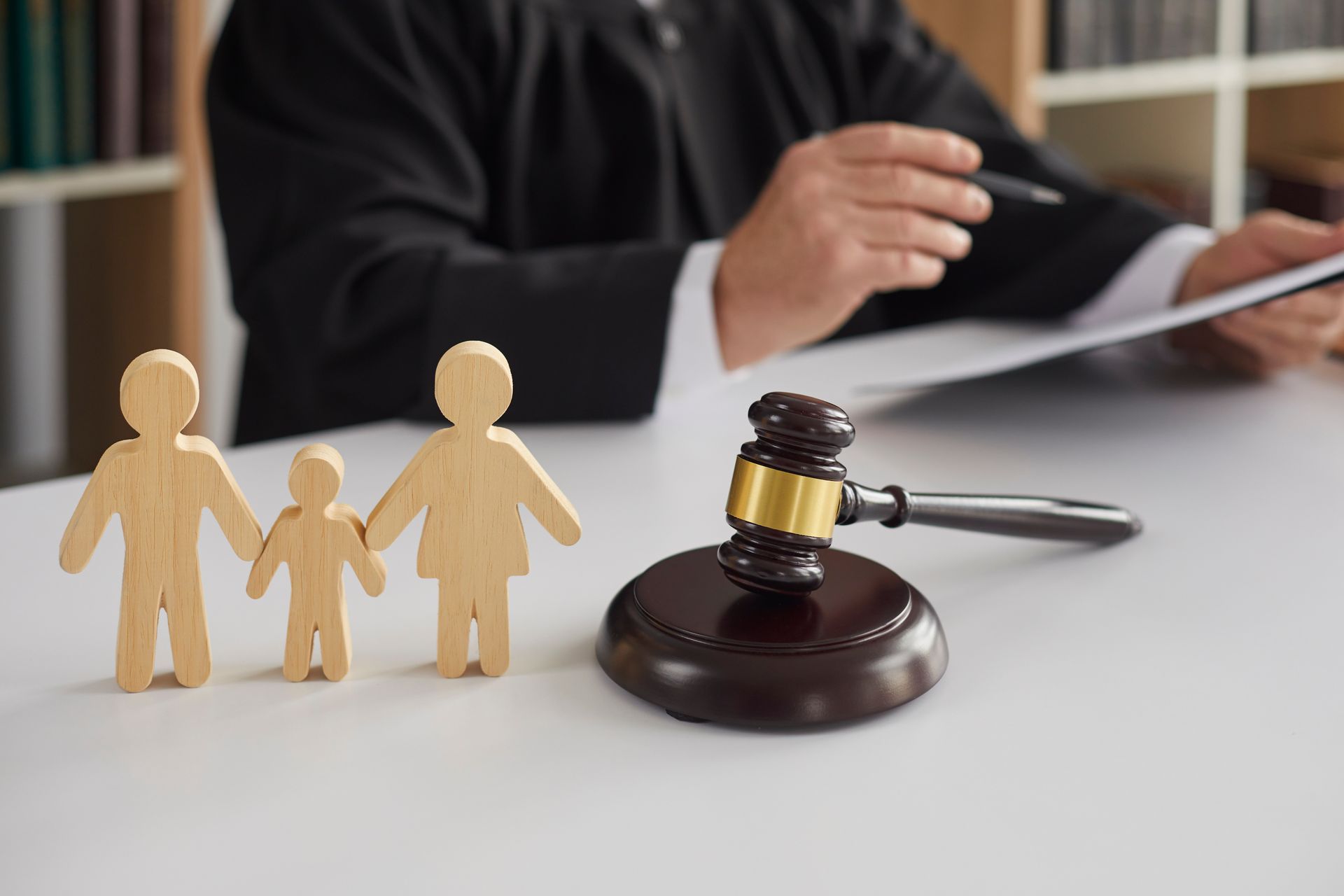 Wooden figurines of a family and a gavel on the background of a judge conducting a divorce process