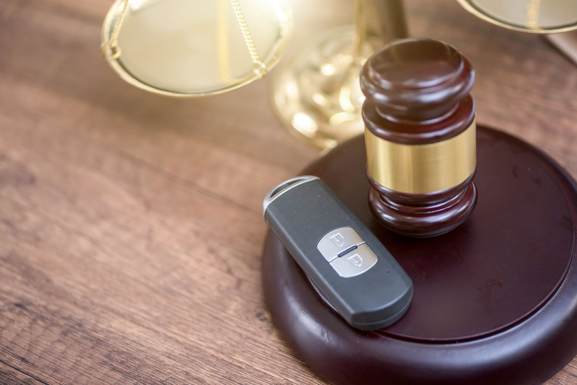 Judge gavel with car key on wooden desk symbolizing auto legal issues and vehicle ownership disputes.