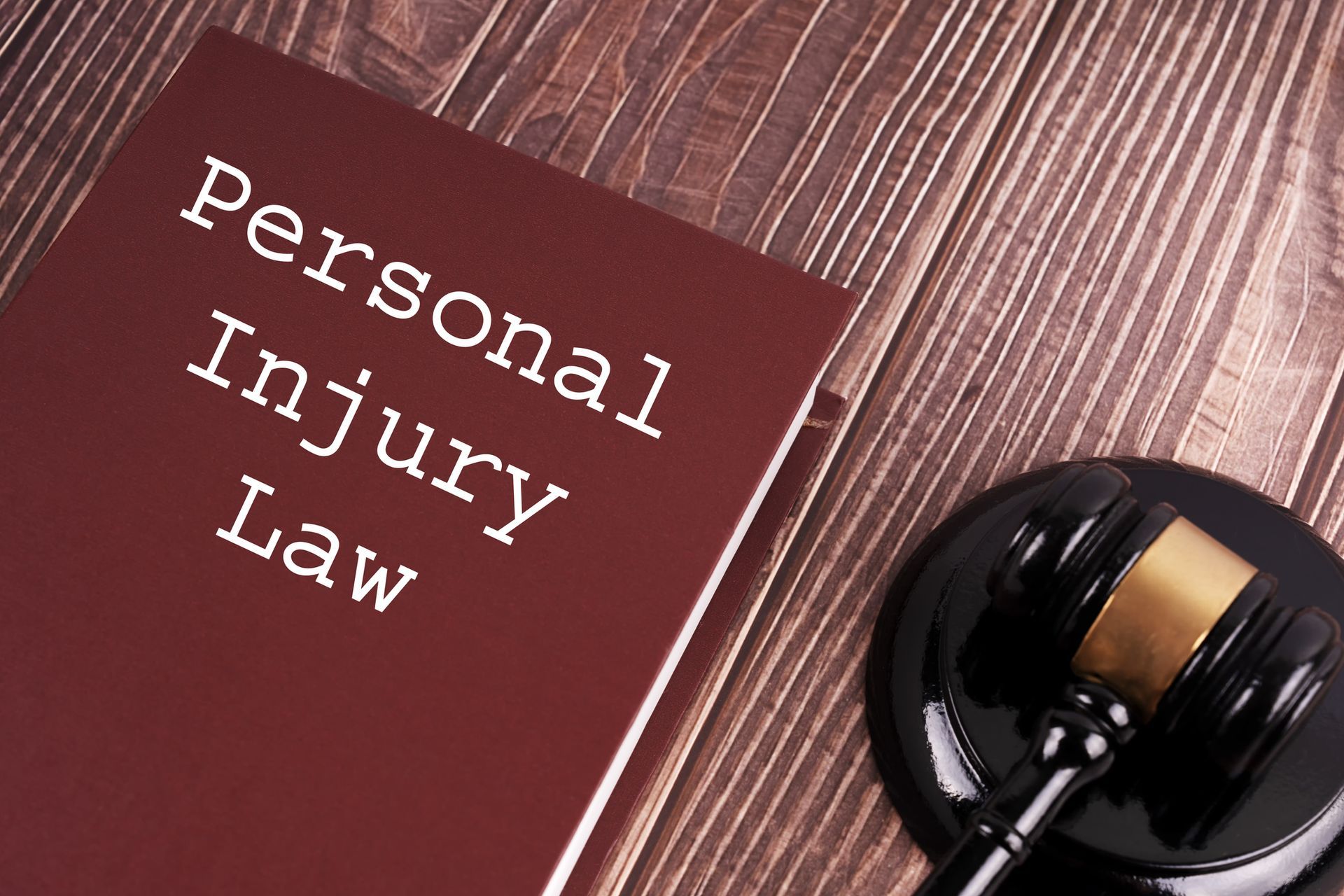 Personal Injury Lawyer book with judge gavel on wooden table—legal advice and justice concept.