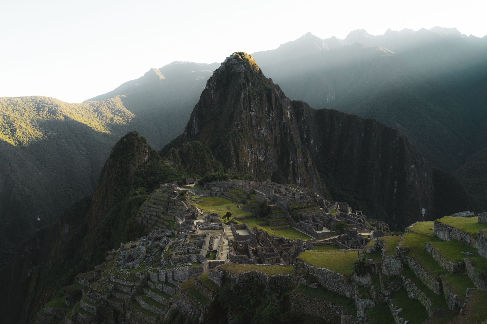 Mountain ruins at Machu Picchu with steep peaks and misty sunlight at dawn