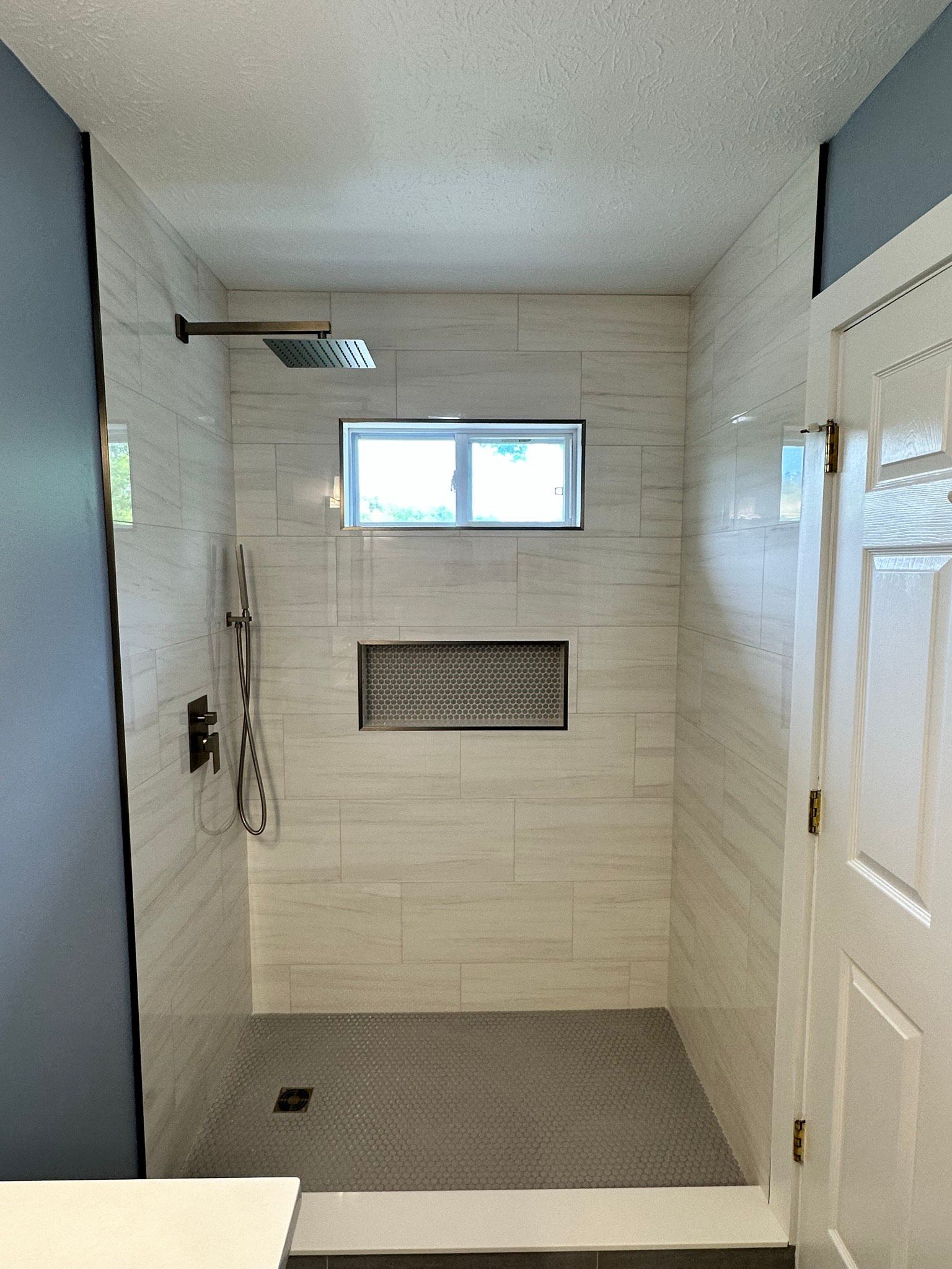 A bathroom with a walk in shower and a window.