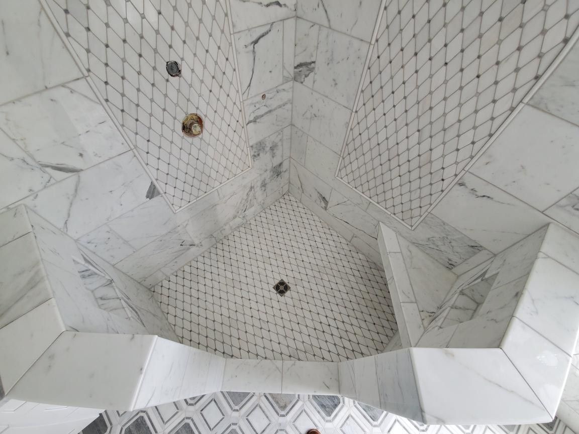 A bathroom with marble tiles and a walk in shower.