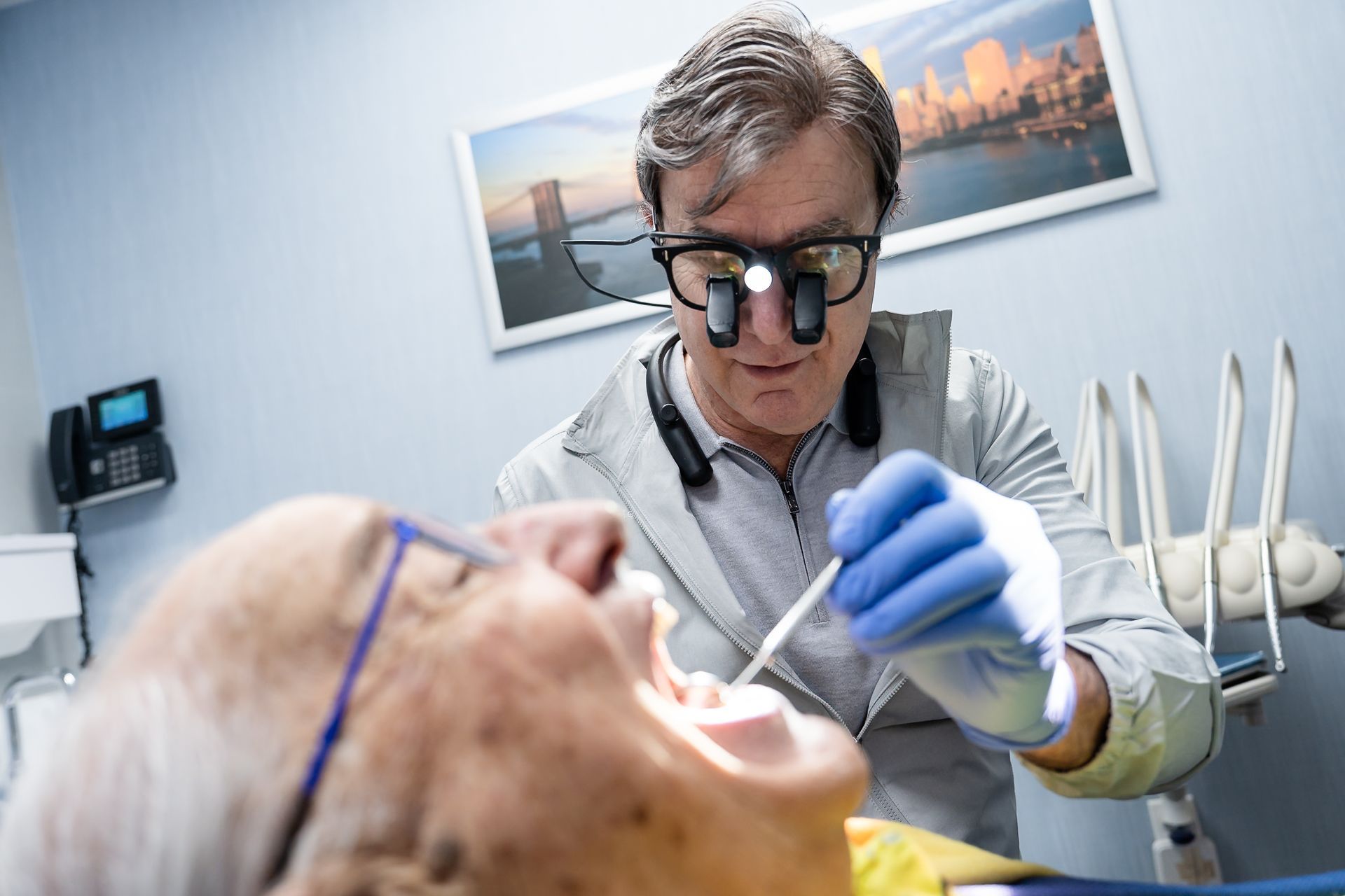 Dentist performing dental work on a patient in a bright, clinical office.
